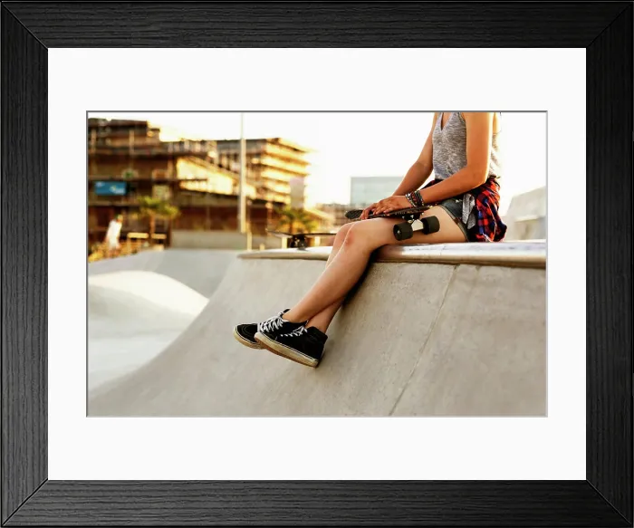 Framed Print : Skateboarder taking a break at a skatepark during golden hour