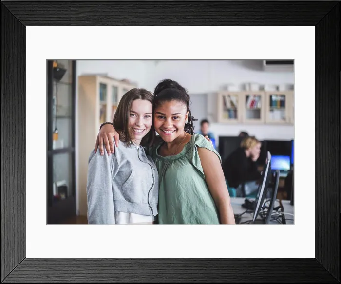 Framed Print : Portrait of smiling female teenage friends standing with arm around in computer lab at high school Framed Print : Portrait of smiling female teenage friends standing with arm around in computer lab at high school