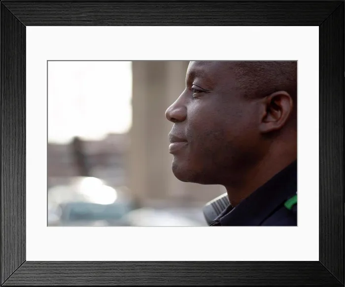 Framed Print : Close up profile Portrait of uniformed Police officer sitting outside looking off camera Framed Print : Close up profile Portrait of uniformed Police officer sitting outside looking off camera