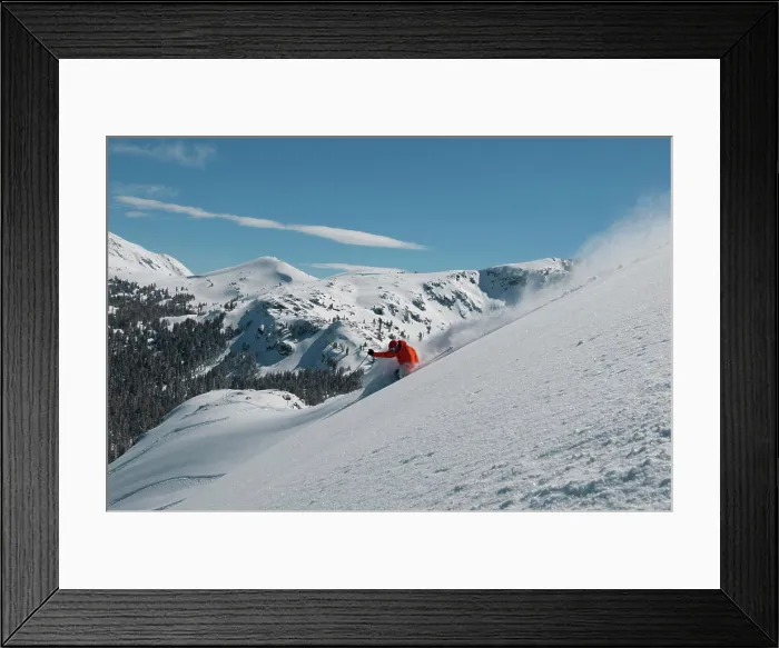Framed Print : A male skier wearing a bright orange jacket makes a series of powder turns on a powder day at a Mountain Resort