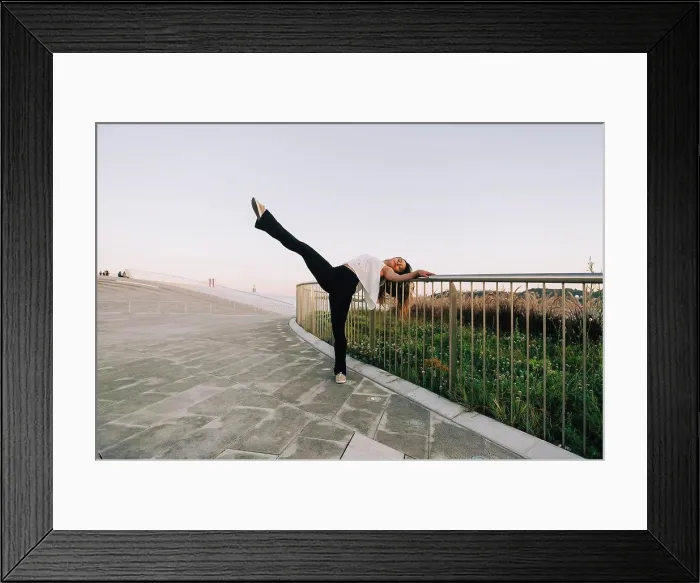 Framed Print : Portrait carefree young female dancer doing standing splits at park railing Framed Print : Portrait carefree young female dancer doing standing splits at park railing