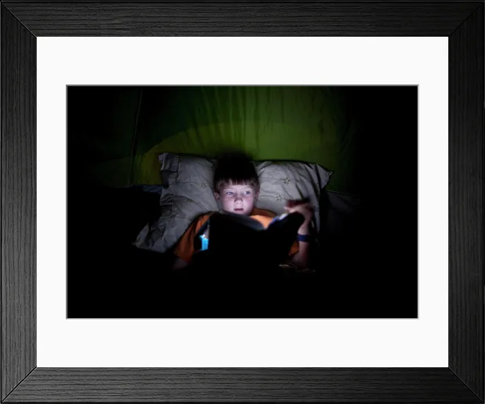 Framed Print : Boy, 9, reading in camping tent by light Framed Print : Boy, 9, reading in camping tent by light