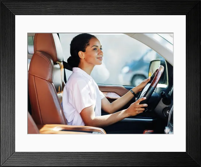 Framed Print : Selbstbewusste junge Frau am Steuer eines Autos Framed Print : Selbstbewusste junge Frau am Steuer eines Autos