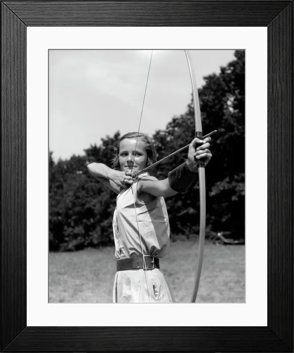 Framed Print : 1930S Girl Wearing A Camp Jumper With Wide Leather Belt About To Release An Arrow From Bow Framed Print : 1930S Girl Wearing A Camp Jumper With Wide Leather Belt About To Release An Arrow From Bow