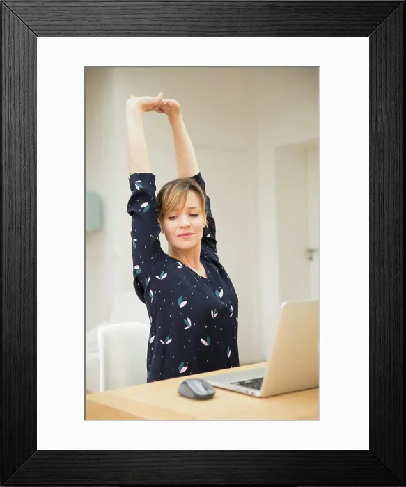 Framed Print : Woman stretching in front of laptop Framed Print : Woman stretching in front of laptop