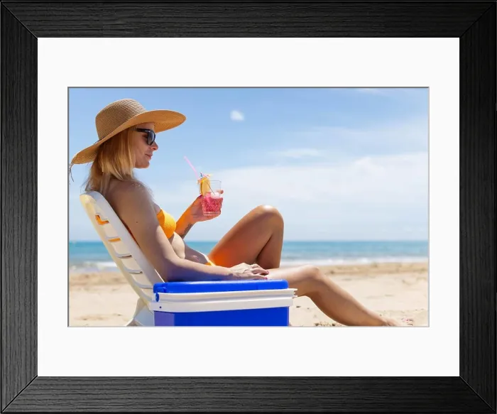 Framed Print : Happy young european girl drinks a cocktail and rests in a sun lounger on the beach Framed Print : Happy young european girl drinks a cocktail and rests in a sun lounger on the beach