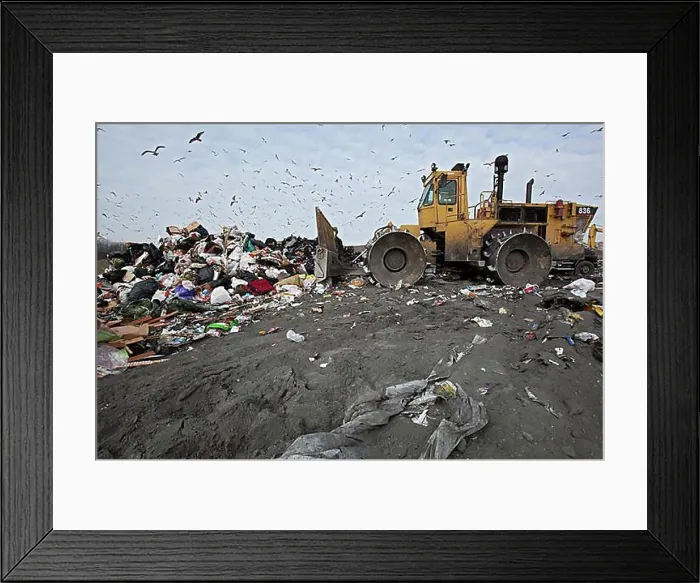 Framed Print : A bulldozer levels and compacts garbage at St