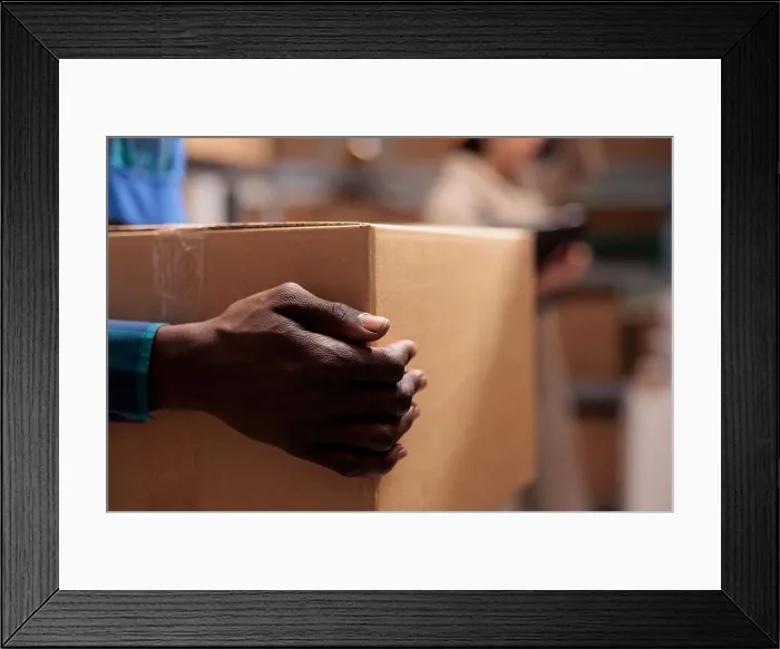 Framed Print : Shipping service warehouse worker holding received parcel in hands Framed Print : Shipping service warehouse worker holding received parcel in hands