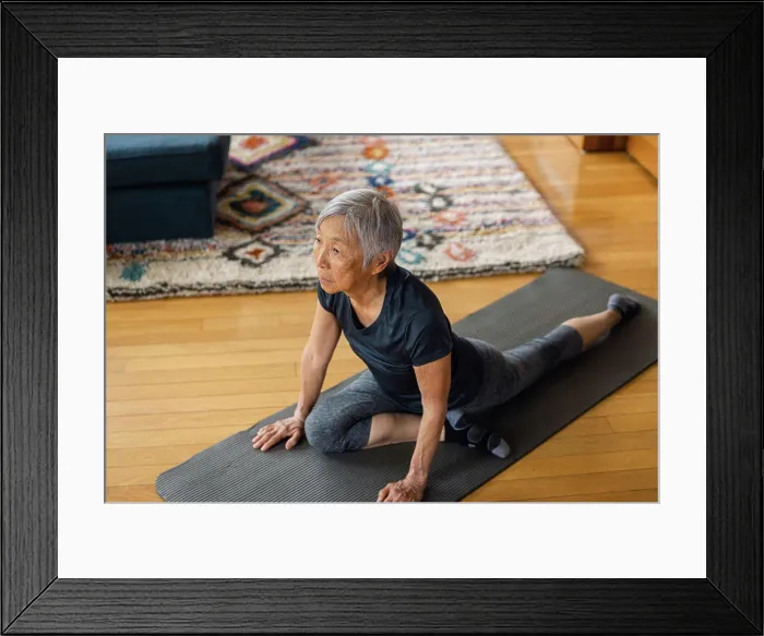 Framed Print : Senior asian woman stretching on exercise mat in living room Framed Print : Senior asian woman stretching on exercise mat in living room