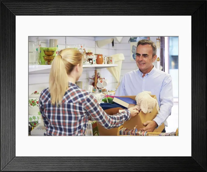 Framed Print : Man Donating Unwanted Items To Charity Shop Framed Print : Man Donating Unwanted Items To Charity Shop
