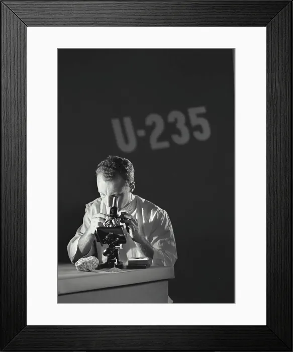 Framed Print : Scientist looking through microscope with U-235 (Uranium Isotope) being projected on the wall Framed Print : Scientist looking through microscope with U-235 (Uranium Isotope) being projected on the wall