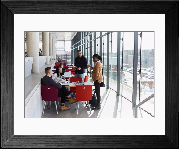 Framed Print : Male and female friends discussing while studying in university cafeteria Framed Print : Male and female friends discussing while studying in university cafeteria