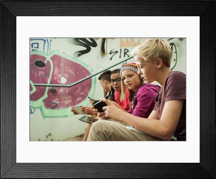 Framed Print : Group of children sitting on stairs outdoors, using tablet computers and smartphones, Germany. 08 / 31 / 2013