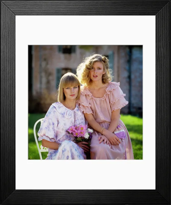 Framed Print : 1970s 1980s TWO BLONDE WOMEN WEARING RUFFLED DRESSES IN PASTEL COLORS SITTING OUTDOORS LOOKING AT CAMERA Framed Print : 1970s 1980s TWO BLONDE WOMEN WEARING RUFFLED DRESSES IN PASTEL COLORS SITTING OUTDOORS LOOKING AT CAMERA