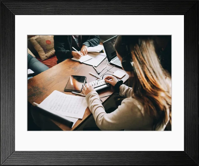 Framed Print : High angle view of teenage girl using audio equipment while doing homework at table in room Framed Print : High angle view of teenage girl using audio equipment while doing homework at table in room