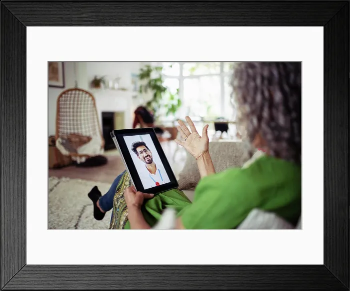 Framed Print : Woman video chatting with doctor on digital tablet screen