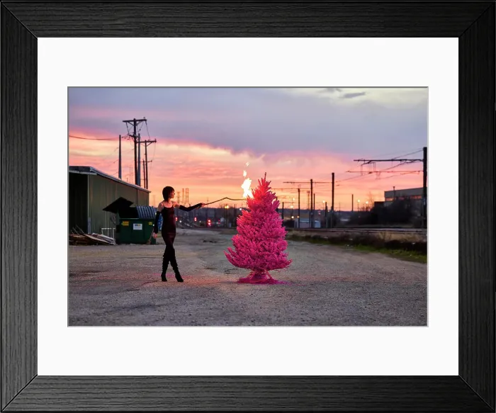 Framed Print : Woman sets fire to pink Christmas tree in industrial area at sunset