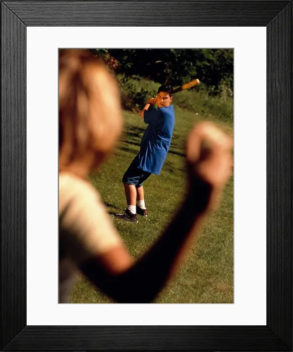 Framed Print : Woman throws a baseball to a young man waiting to hit the ball with a bat