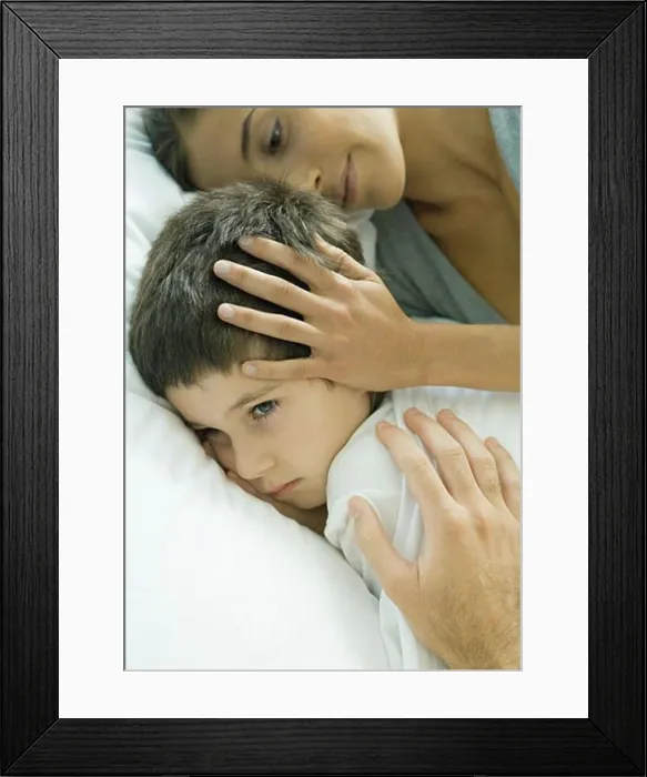 Framed Print : Child lying in bed, parent's hands on head and shoulder Framed Print : Child lying in bed, parent's hands on head and shoulder