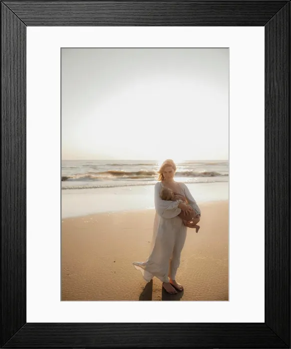 Framed Print : Mother holding baby on the beach by the ocean at sunset
