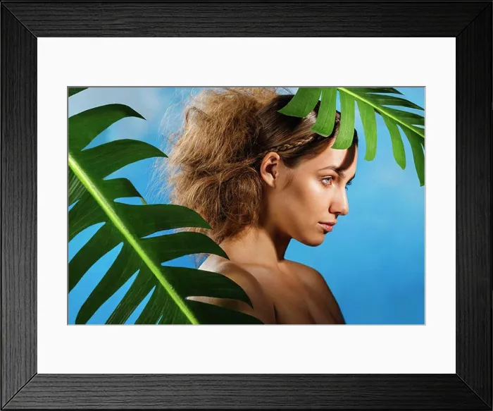 Framed Print : Thoughtful naked woman with palm leaves against blue sky Framed Print : Thoughtful naked woman with palm leaves against blue sky