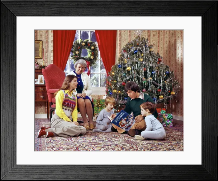 Framed Print : 1970s FAMILY READING CHRISTMAS BOOK MOTHER FATHER SONS GRANDMOTHER