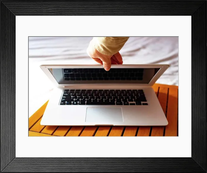 Framed Print : Hand closing the white laptop. Framed Print : Hand closing the white laptop.