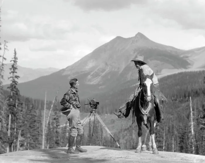 Framed Print : 1930S Cameraman In Boots Jodhpurs & Wool Hunting Shirt Standing Next To Movie Camera On Tripod Talking To Mounted Cowboy Framed Print : 1930S Cameraman In Boots Jodhpurs & Wool Hunting Shirt Standing Next To Movie Camera On Tripod Talking To Mounted Cowboy