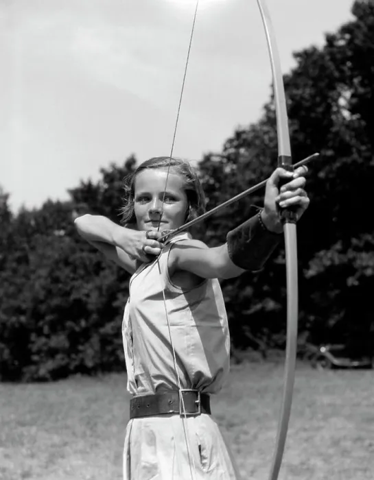 Framed Print : 1930S Girl Wearing A Camp Jumper With Wide Leather Belt About To Release An Arrow From Bow Framed Print : 1930S Girl Wearing A Camp Jumper With Wide Leather Belt About To Release An Arrow From Bow