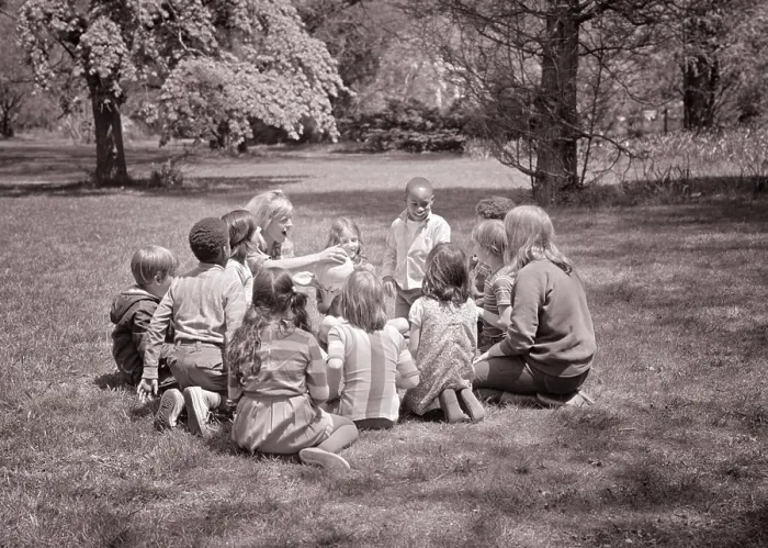 Framed Print : 1960s ADULT WOMAN TEACHER HANDING A BALL TO ETHNICALLY MIXED GROUP OF CHILDREN VARIOUS AGES SITTING IN CIRCLE ON THE Framed Print : 1960s ADULT WOMAN TEACHER HANDING A BALL TO ETHNICALLY MIXED GROUP OF CHILDREN VARIOUS AGES SITTING IN CIRCLE ON THE