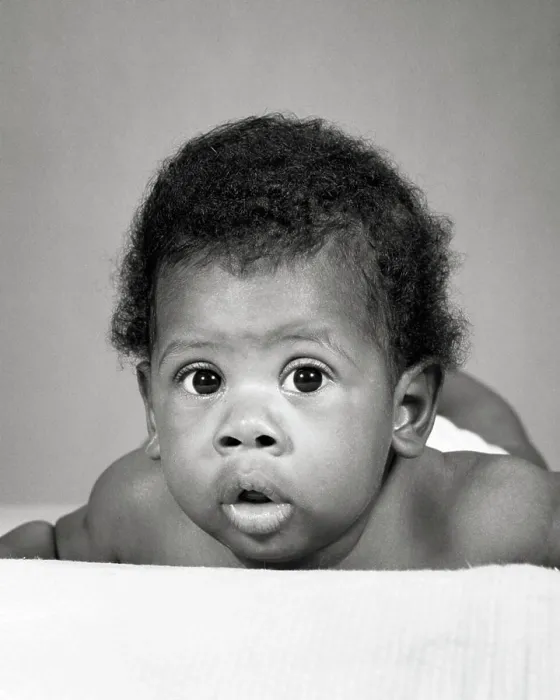 Framed Print : 1960s AFRICAN-AMERICAN BABY LAYING ON STOMACH FUNNY FACIAL EXPRESSION
