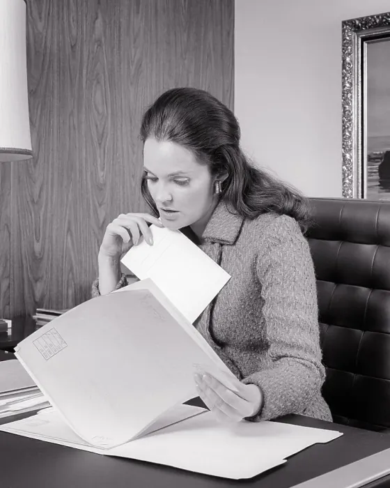 Framed Print : 1970s WOMAN ADMINISTRATOR INTENTLY FOCUSED ON REVIEWING CONTENTS OF A FILE SEATED AT HER DESK - o3331 HAR001 HARS