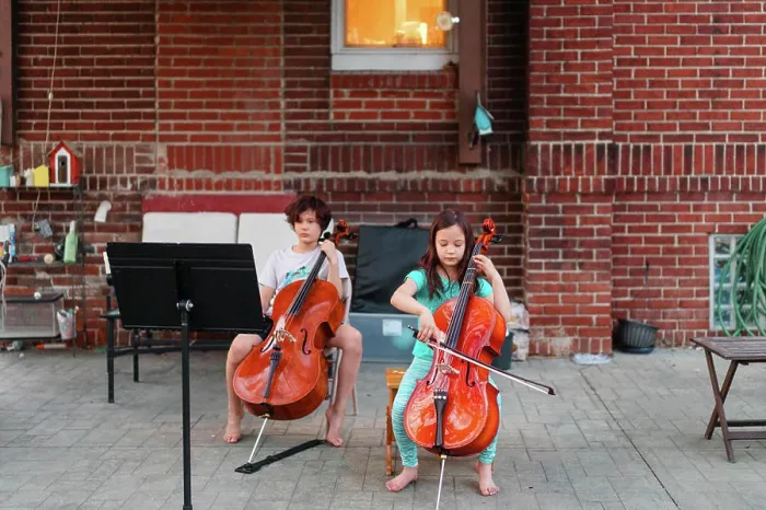 Framed Print : Above-view of two children sitting on patio playing cello Framed Print : Above-view of two children sitting on patio playing cello
