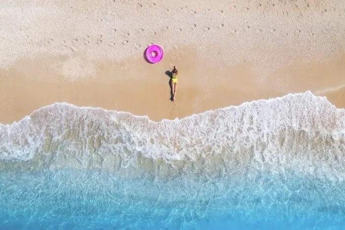 Framed Print : Aerial view of the lying beautiful young woman with pink swim ring on the sandy beach near sea with waves at sunset Framed Print : Aerial view of the lying beautiful young woman with pink swim ring on the sandy beach near sea with waves at sunset