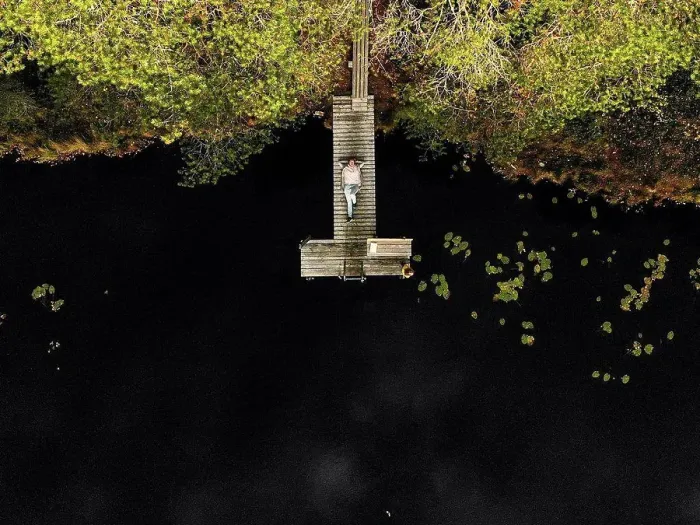 Framed Print : Aerial view of woman lying on pier over lake in forest Framed Print : Aerial view of woman lying on pier over lake in forest