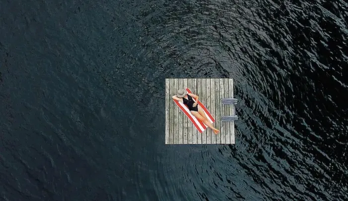 Framed Print : Aerial of woman relaxing alone on floating dock on lake in summer Framed Print : Aerial of woman relaxing alone on floating dock on lake in summer