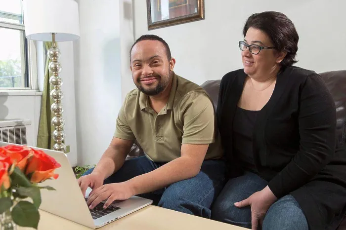 Framed Print : African American man with Down Syndrome using a laptop with his mother at home