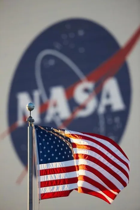 Framed Print : American flag in foreground and large NASA insignia on the side of the Vehicle Assembly Building (VAB)