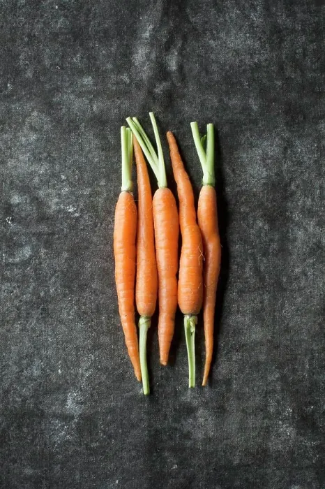 Framed Print : Five baby carrots next to each other on a grey surface