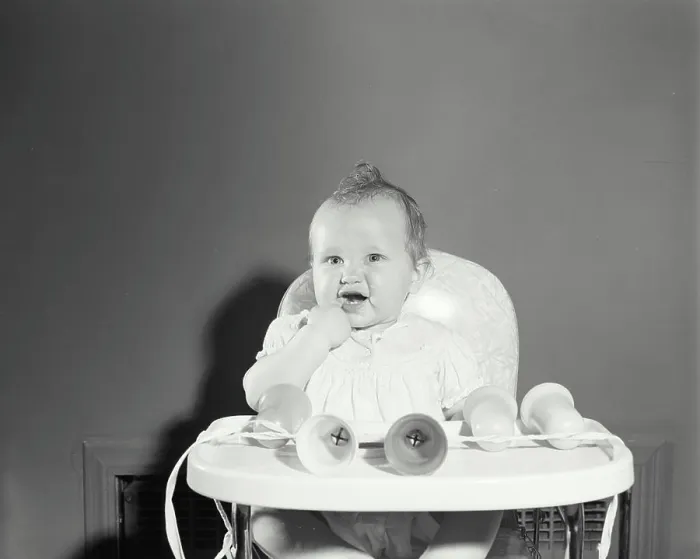 Framed Print : Baby girl sitting in a high chair with her finger in her mouth Framed Print : Baby girl sitting in a high chair with her finger in her mouth