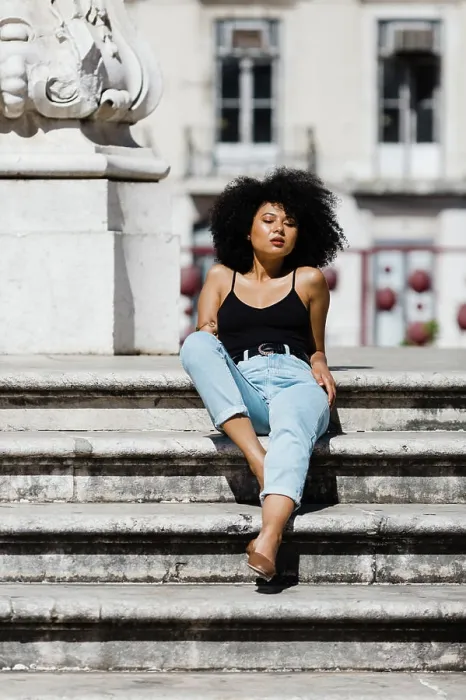 Framed Print : Beautiful ethnic woman in jeans and tank top relaxing and sunbathing on stone stairs against urban background