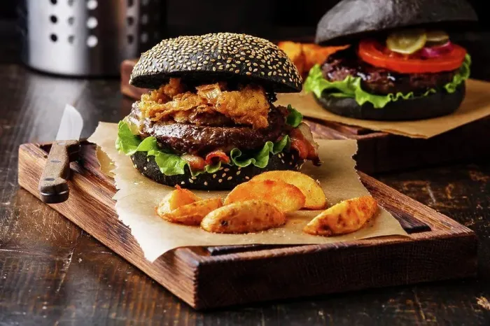 Framed Print : Black burger with sesame seed bun, meat, bacon, onion fries rings and potato wedges on dark wooden background Framed Print : Black burger with sesame seed bun, meat, bacon, onion fries rings and potato wedges on dark wooden background