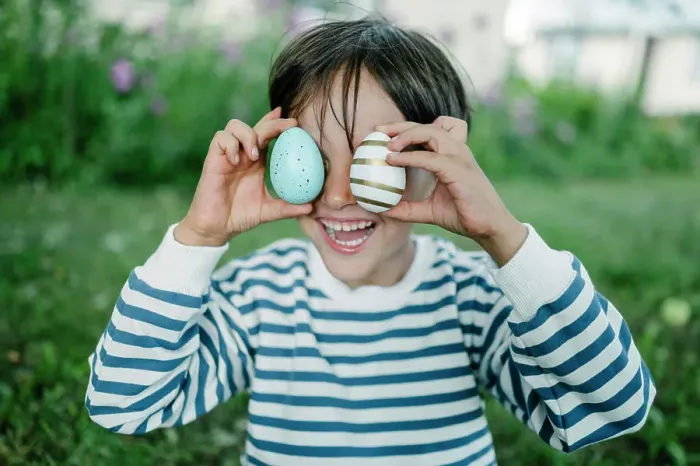 Framed Print : Boy covering eyes with easter eggs in park