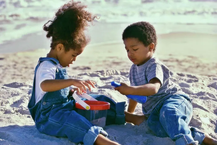 Framed Print : Boy and a girl playing with a sand pail and a shovel on the beach