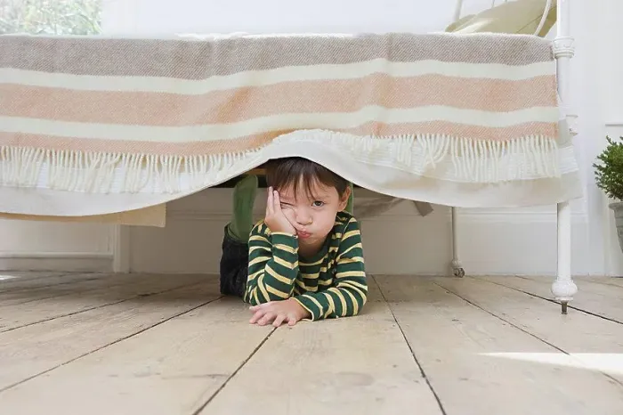Framed Print : Boy hiding under a bed
