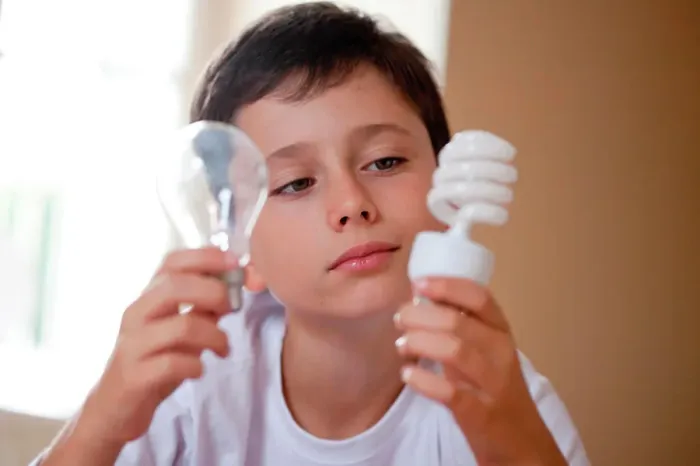Framed Print : Boy holding energy saving lightbulb (right) and incandescent lightbulb (left) Framed Print : Boy holding energy saving lightbulb (right) and incandescent lightbulb (left)