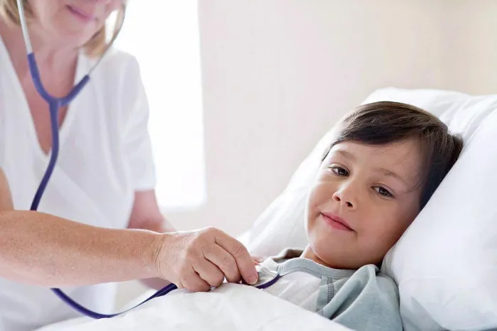 Framed Print : Boy in hospital bed, nurse using stethoscope