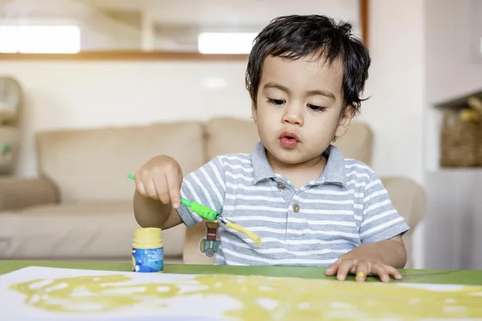 Framed Print : Boy paints with tempera colors paints in her living room
