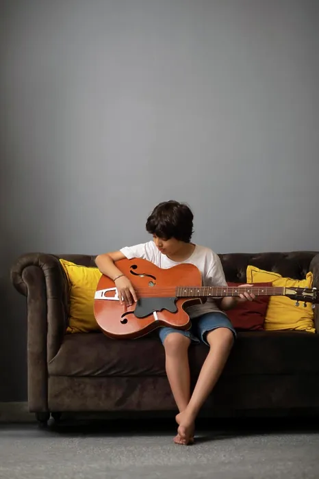 Framed Print : Boy playing guitar in living room Framed Print : Boy playing guitar in living room