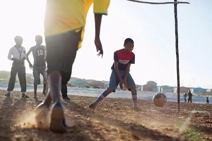 Framed Print : Boys playing soccer together in dirt field